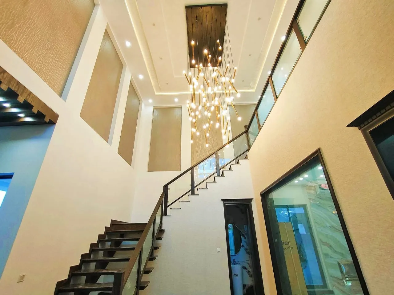 Double-height stair void with a floating timber staircase and a suspended chandelier